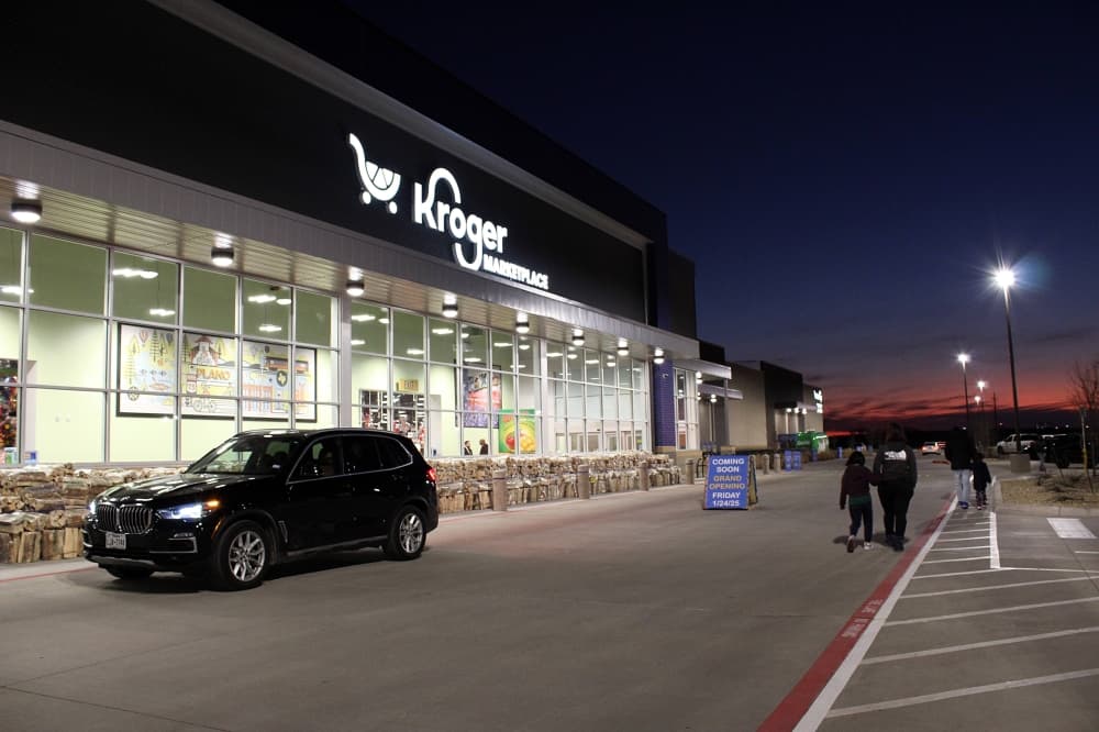 Exterior of a building at night with Kroger signage and sunset in the background. 
