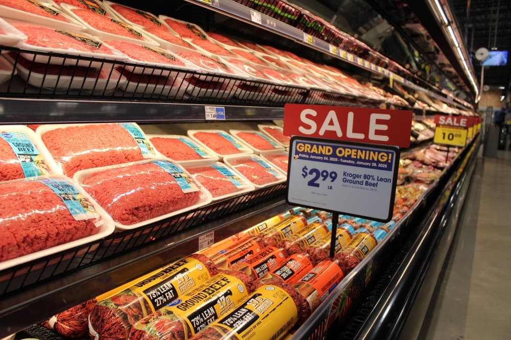 Raw meat in a grocery store case with Sale Grand Opening signage. 