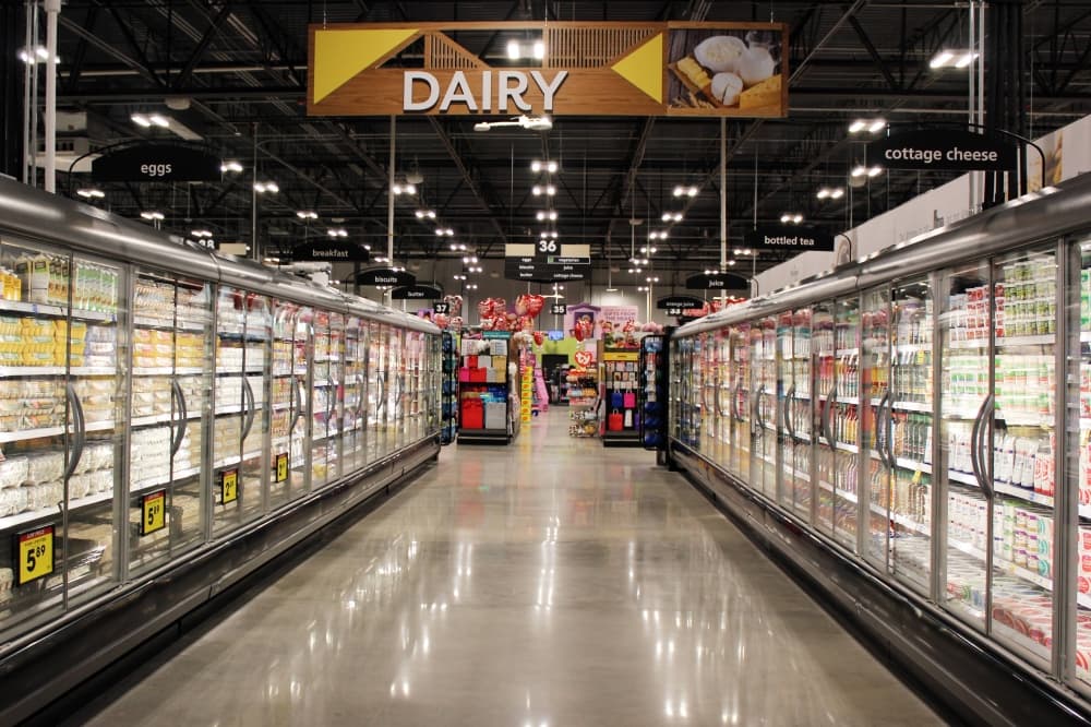 Cooler cases lining a walkway with Dairy signage. 