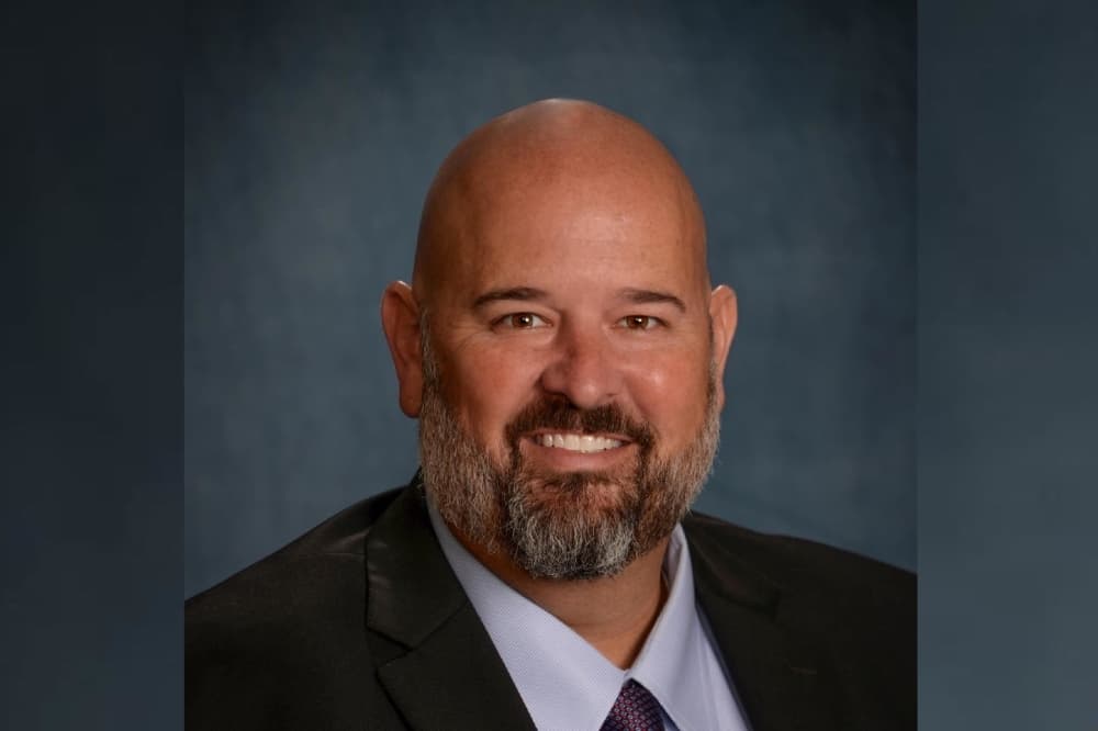 a headshot of a bald man in a suit