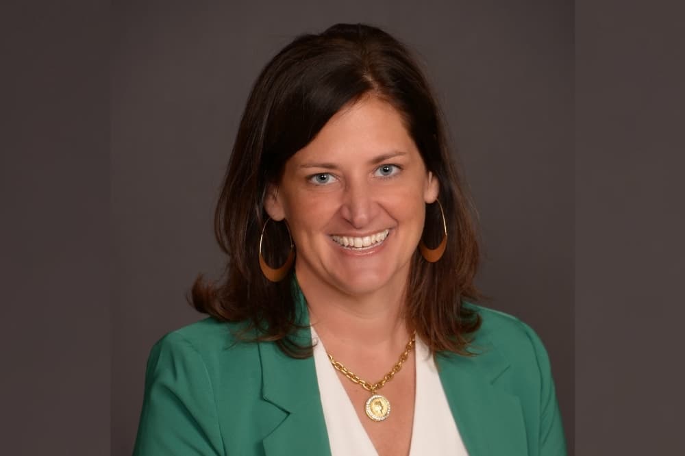 a headshot of a woman in a green blazer jacket