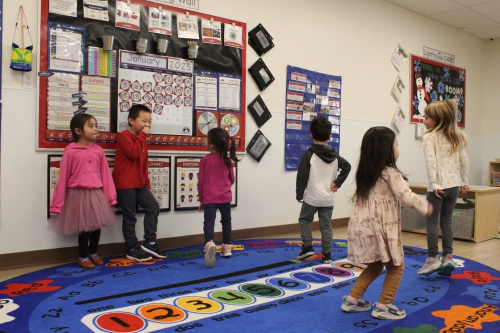 A group of young children dance in a classroom
