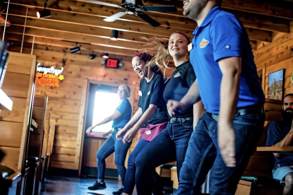 Texas Roadhouse employees doing a dance inside of the restaurant. 