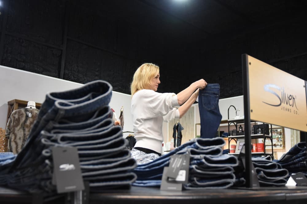 A woman folds jeans in a thrift shop. 