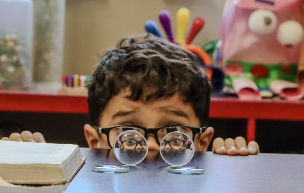 child looking through magnifying glass