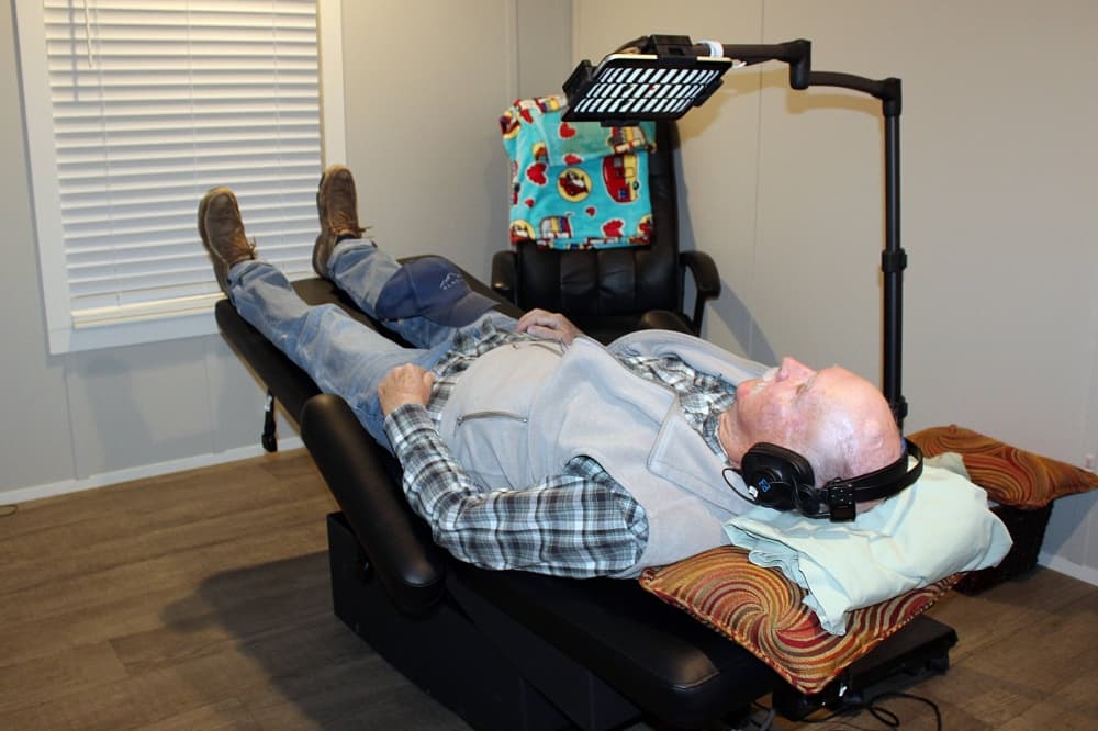 Male lying in a medical-purpose recliner chair while wearing headphones. 