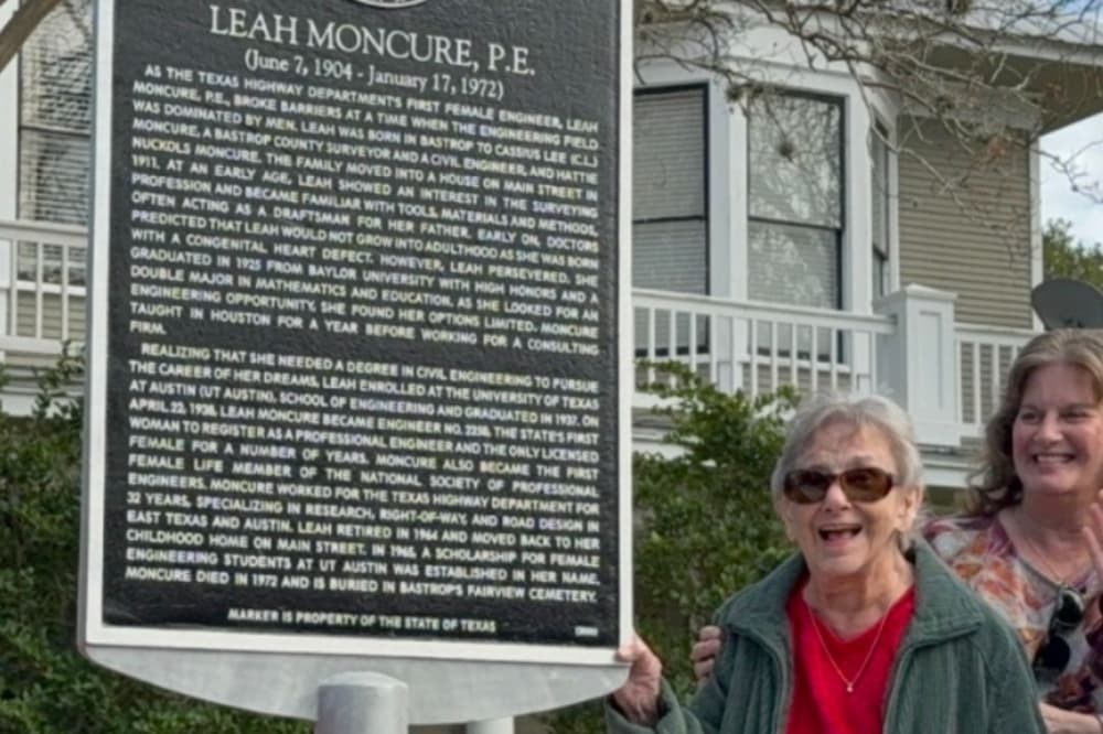 Martha is shown smiling next to the marker in front of the house.