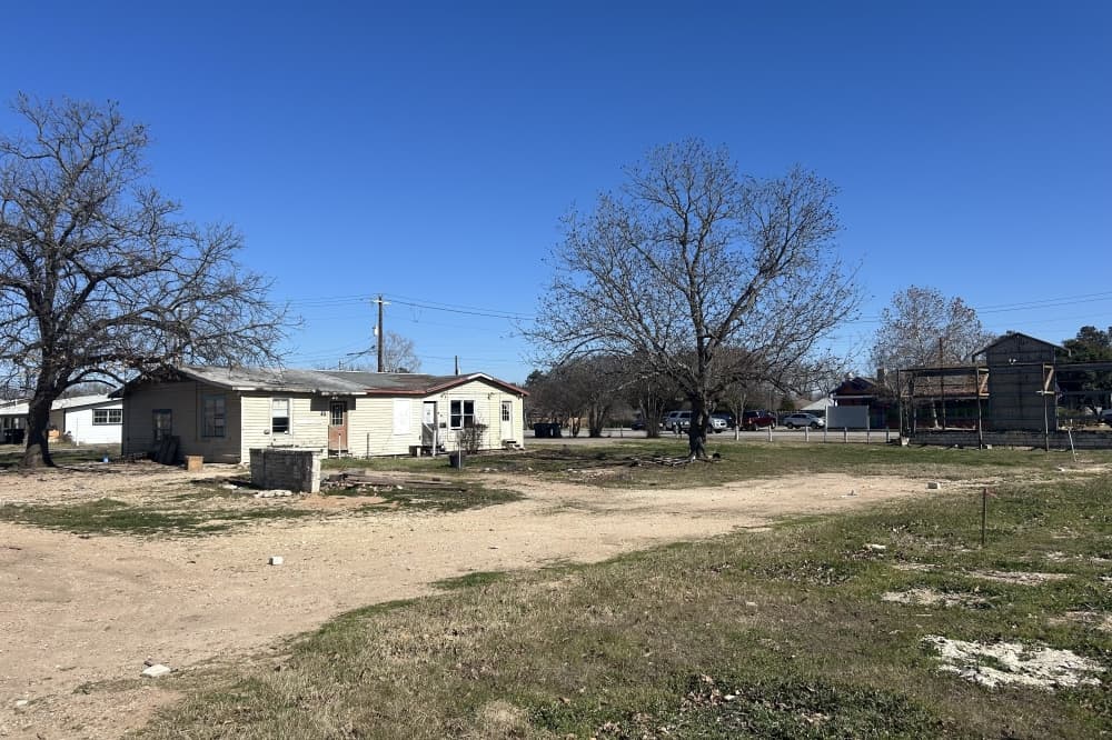 The exterior of a white building with some debris in front of it.