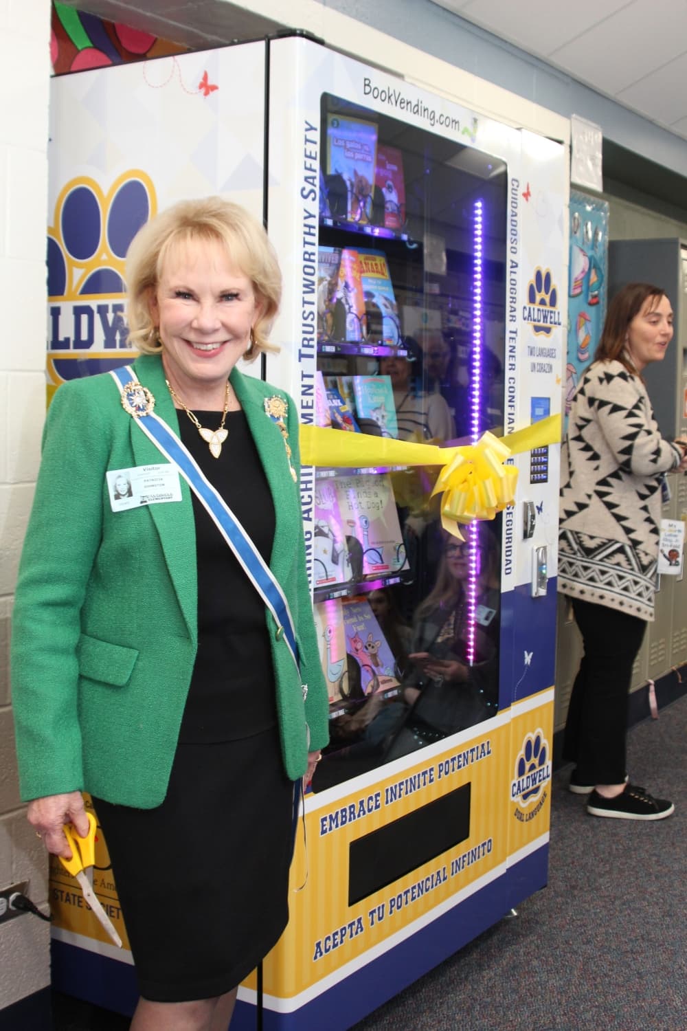 A woman smiles before cutting a ribbon to celebrate the opening of a new book vending machine