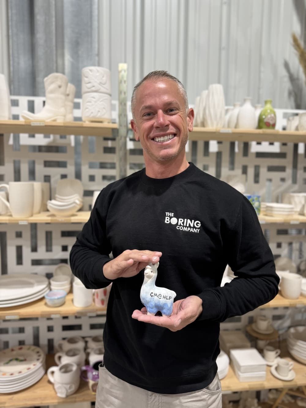 A man is shown holding a llama sculpture he created.