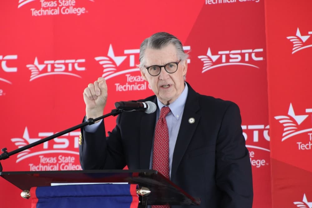 A man points on a podium. 