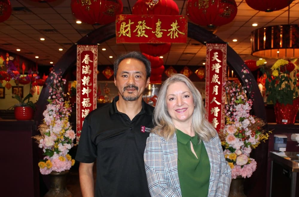 Male and female standing next to each other in a Chinese restaurant. 