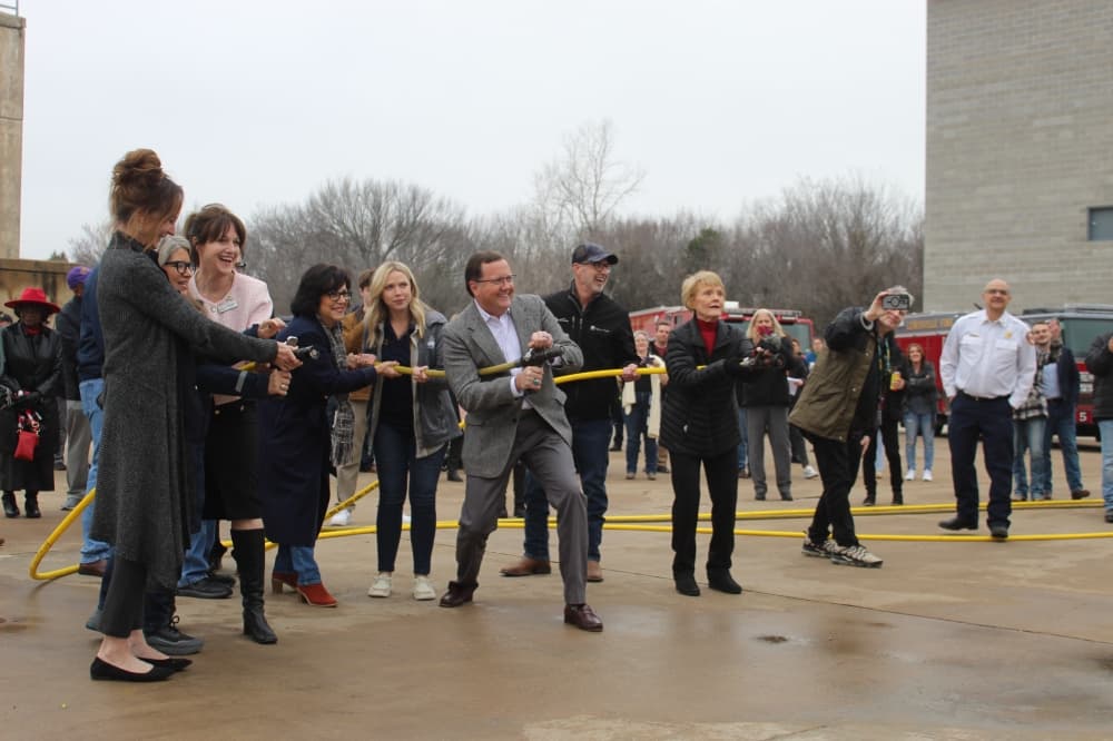 Image of officials from Flower Mound, Highland Village and Flower Mound holding water hoses while they strike a pose for a photographer