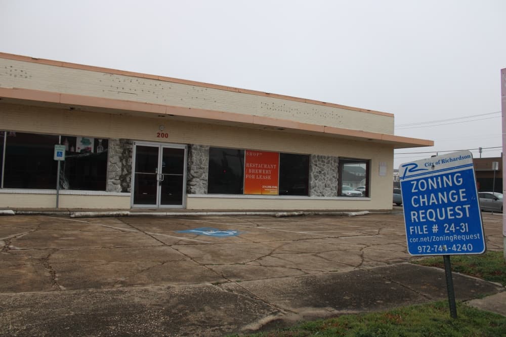 a empty building with a zoning change request in front of it. 