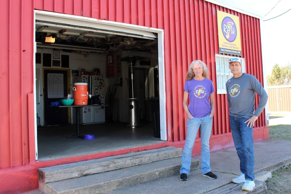 Female and male standing next to each other in front of a red metal building. 