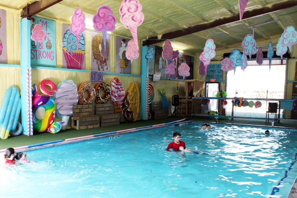 Covered swimming pool with cotton candy art hanging from the rafters. 