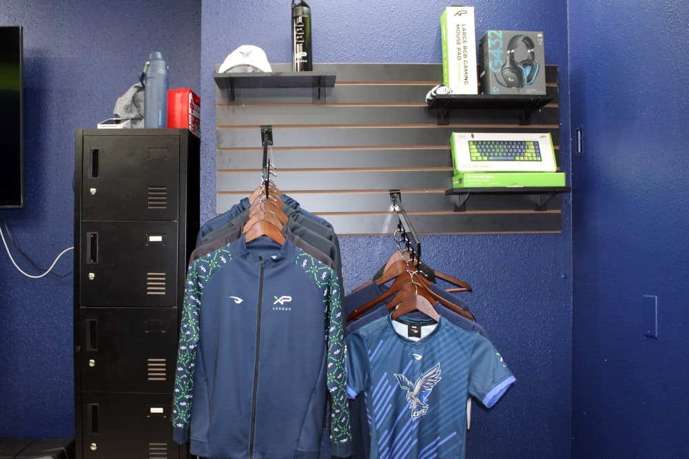 XP League shirts and gaming merchandise on racks and shelves. 