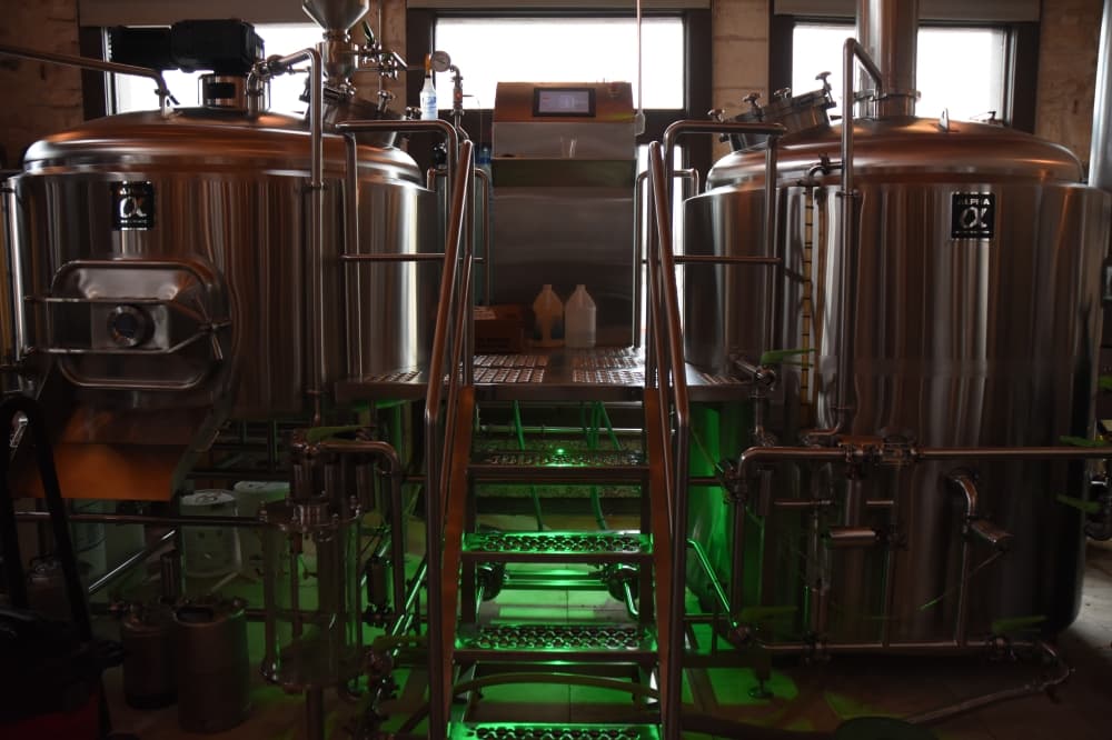 Large metal tanks in a brewery with green underlighting. 