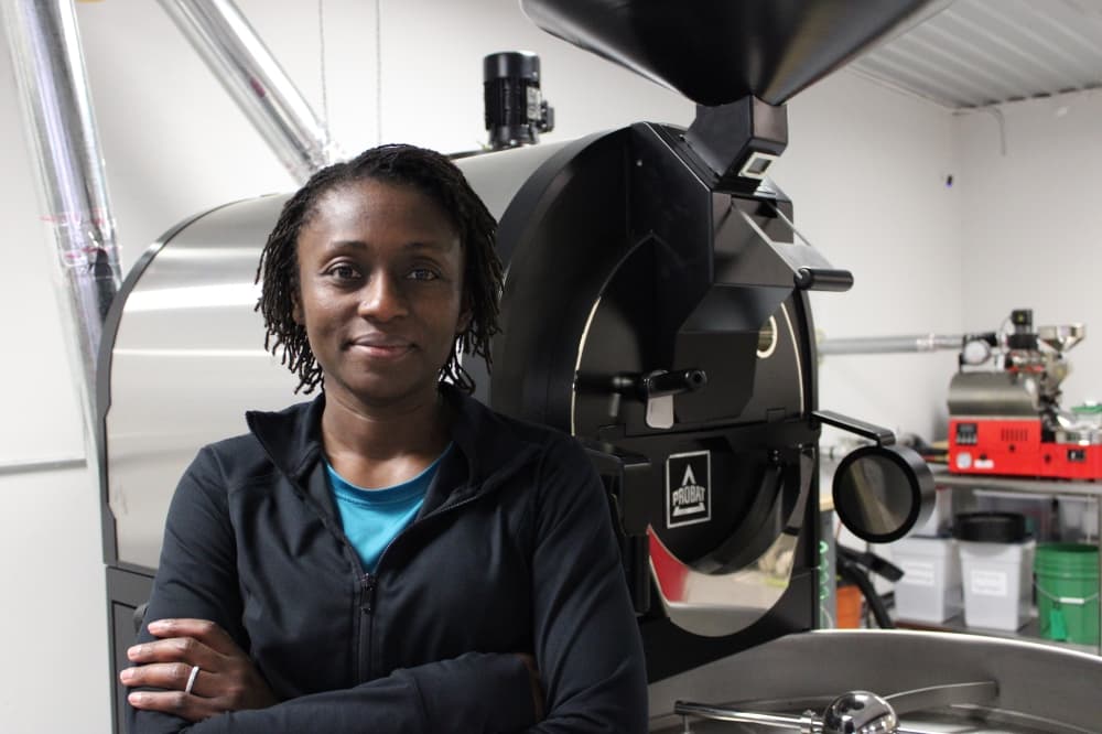 Woman poses in front of roasting machine. 