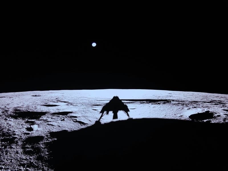 a shadow on the moon's surface depicts a lunar lander on the moon. 