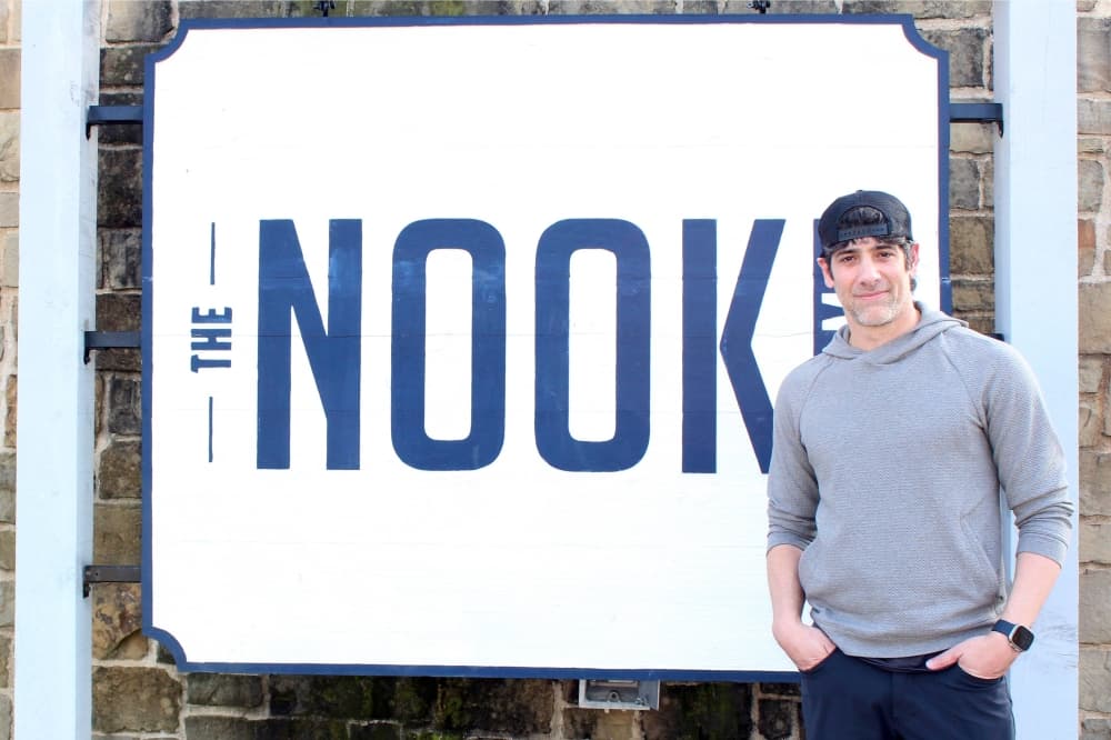 Male standing in front of a sigh with The Nook lettering.