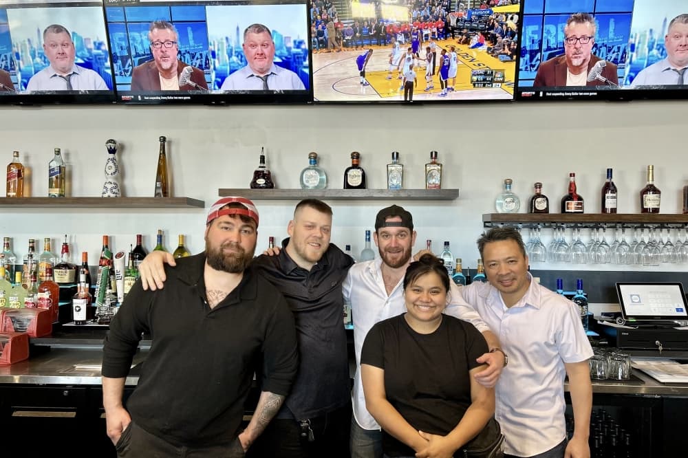 A photo of the owner with staff inside of the restaurant