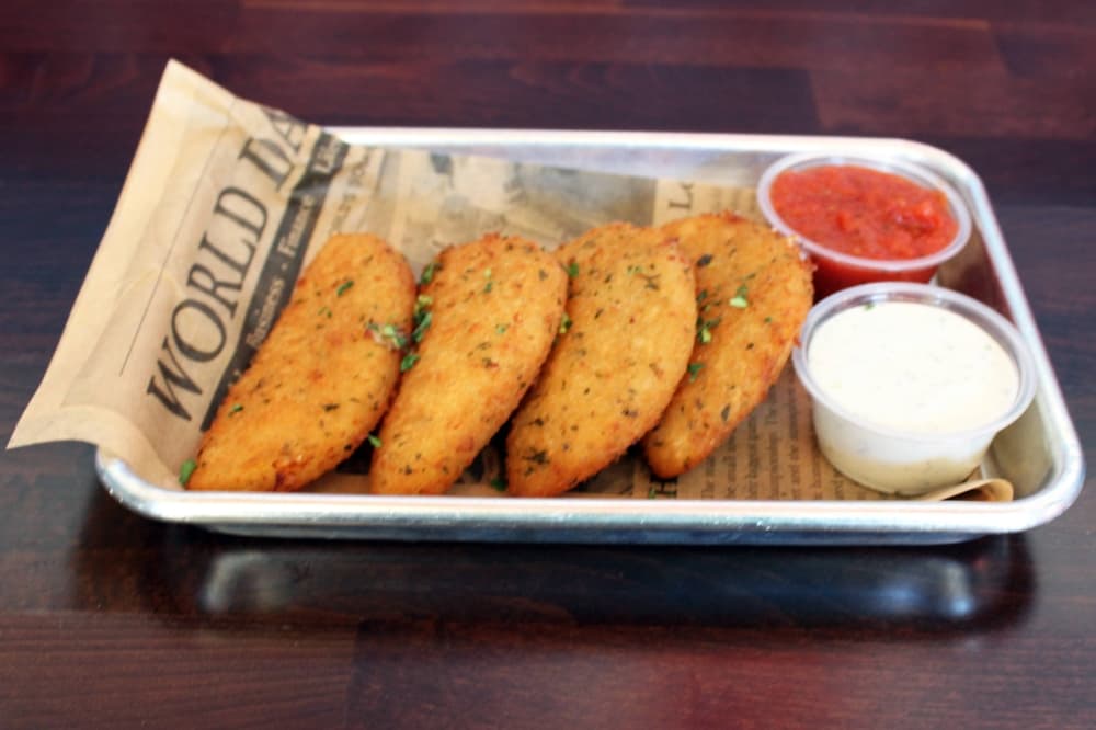 Four half-moon shaped fried items with sides of marinara and ranch dressing. 