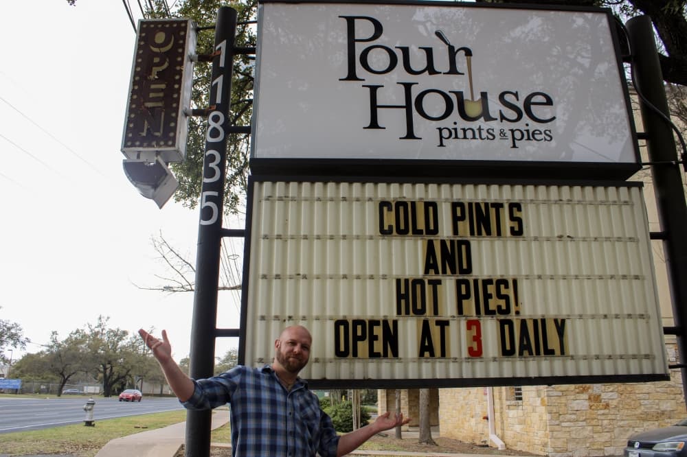 An image of the general manager of the restaurant with the business sign. 