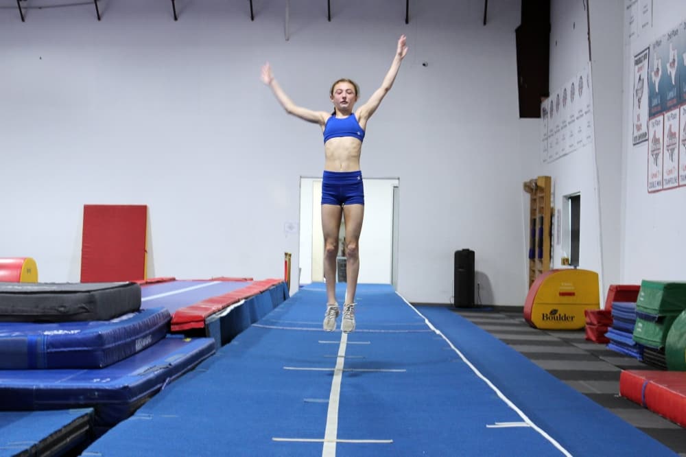 Girl mid-air over a spring board. 