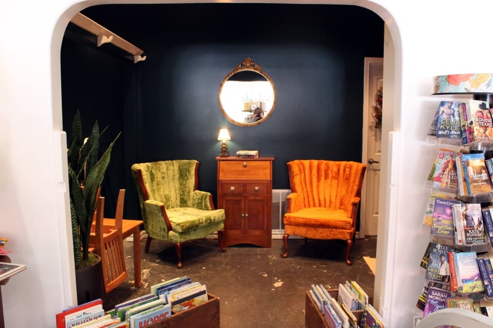 Arched entry to a back room with two brightly colored cloth-covered chairs. 