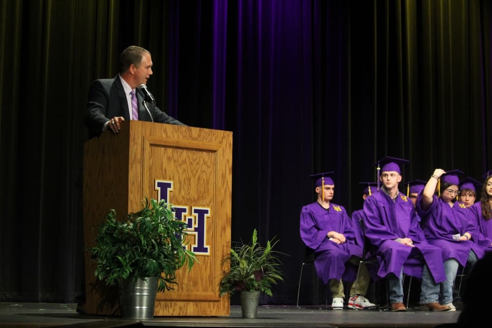 A man in a suit speaks at a podium