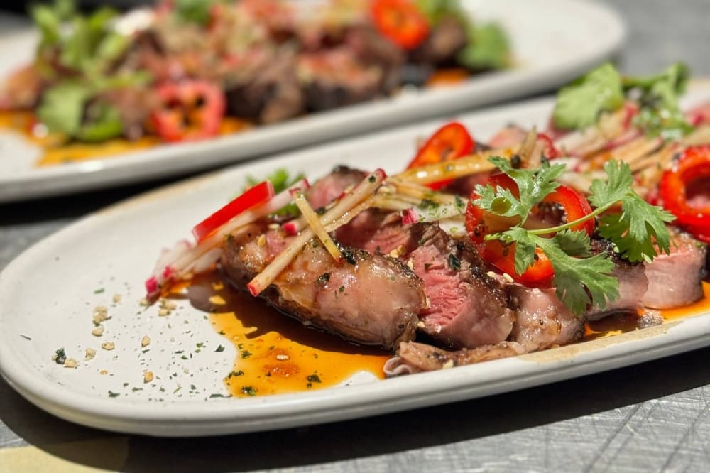Thin slices of steak topped with tomatoes and other vegetables. 