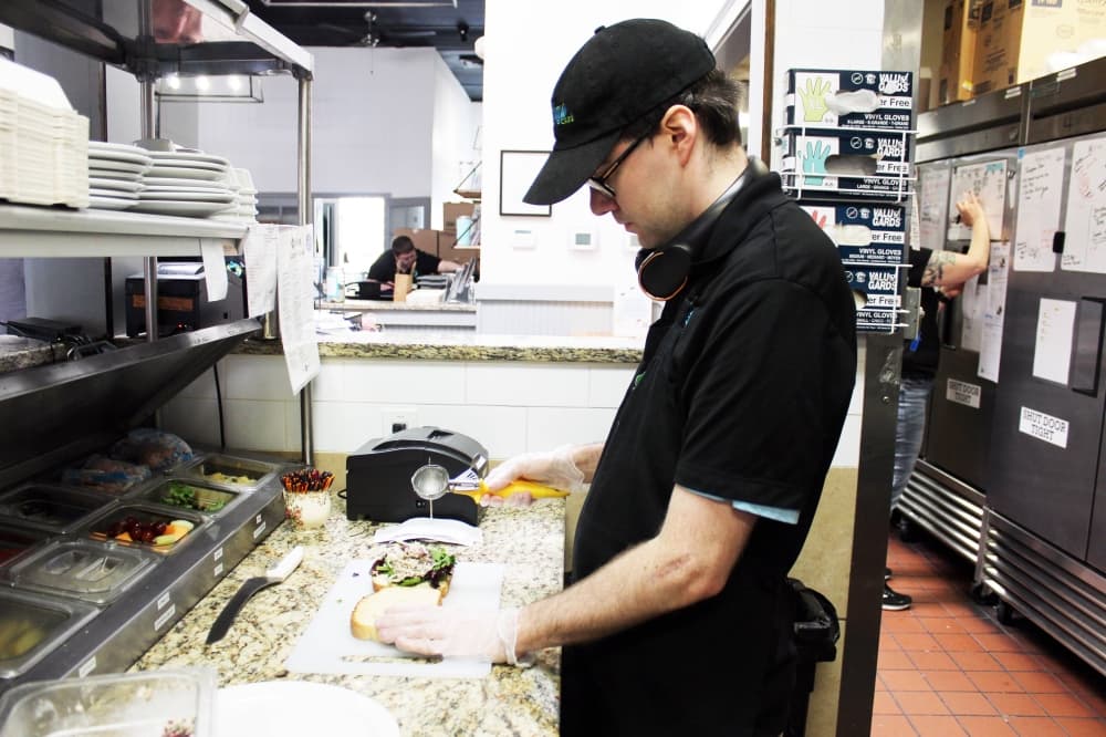 Male making a sandwich in a restaurant kitchen. 