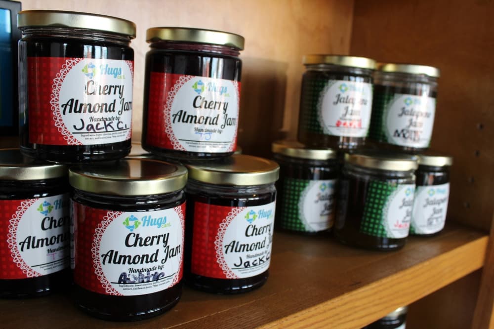 Glass jars stacked in a display shelf with Cherry Almond Jan labels. 