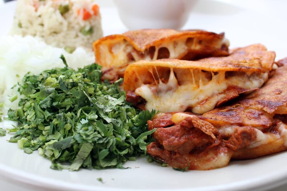Three hard shelled tacos filled with meat and melted cheese. 