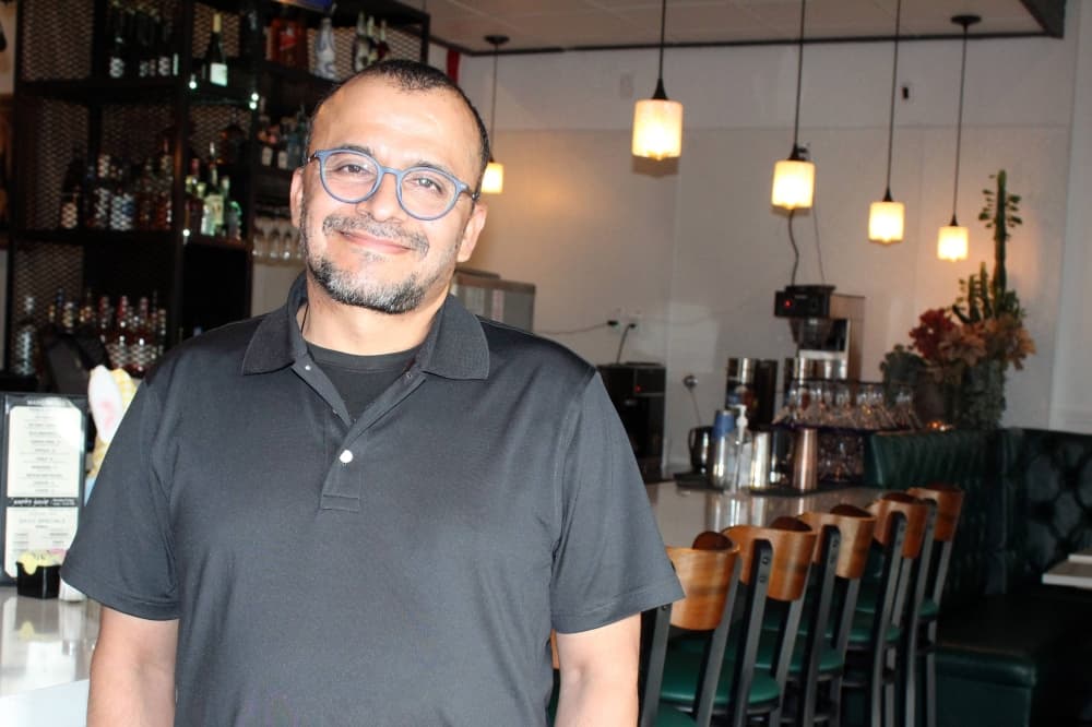 Male standing in front of a bar in a restaurant. 