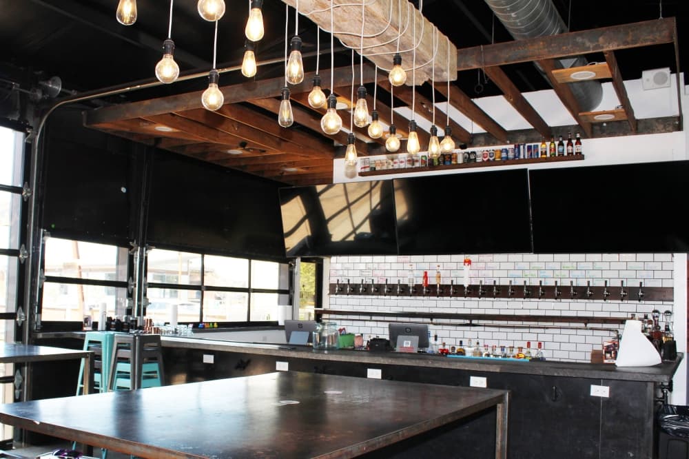 Interior of a bar with large tables and pendant lights. 