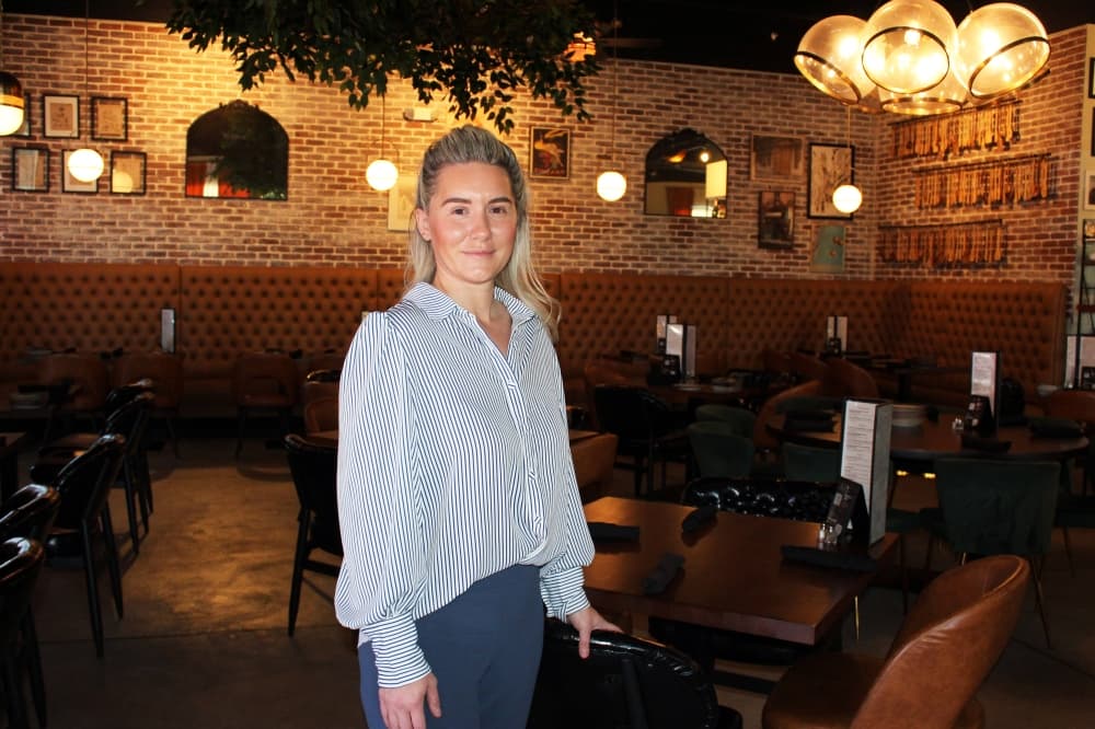 Female standing in a dimly lit restaurant. 