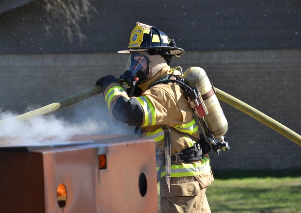 A firefighter spraying water on a dumpster