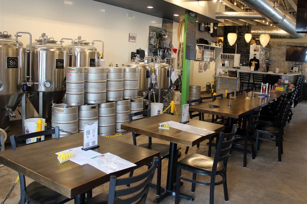 Interior of a business with tables topped with games and brewery equipment against a wall. 