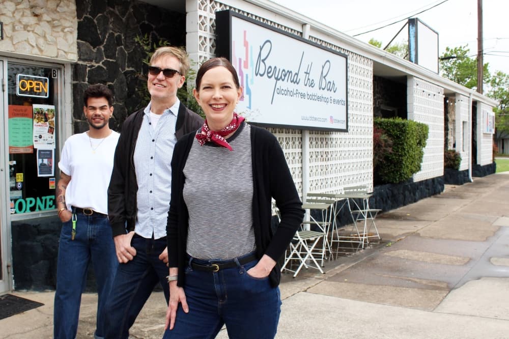 Two mailes and one female standing in front of a building with Beyond the Bar sign. 