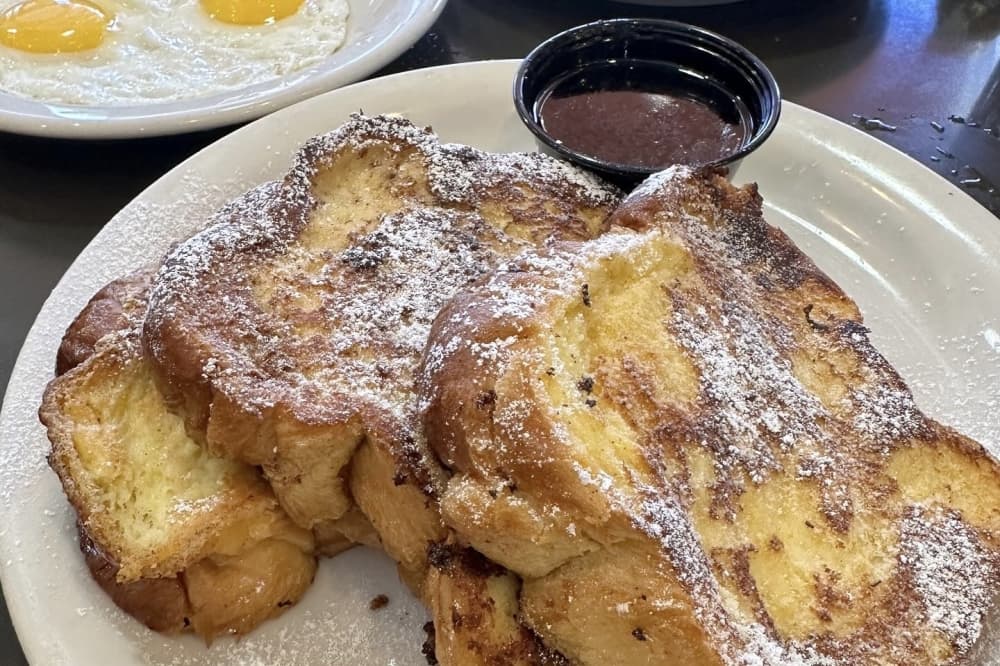 The challah French toast consists of three thick challah bread slices dipped in egg custard and griddled. ($14.95). (Courtesy Max and Louie's New York Diner)