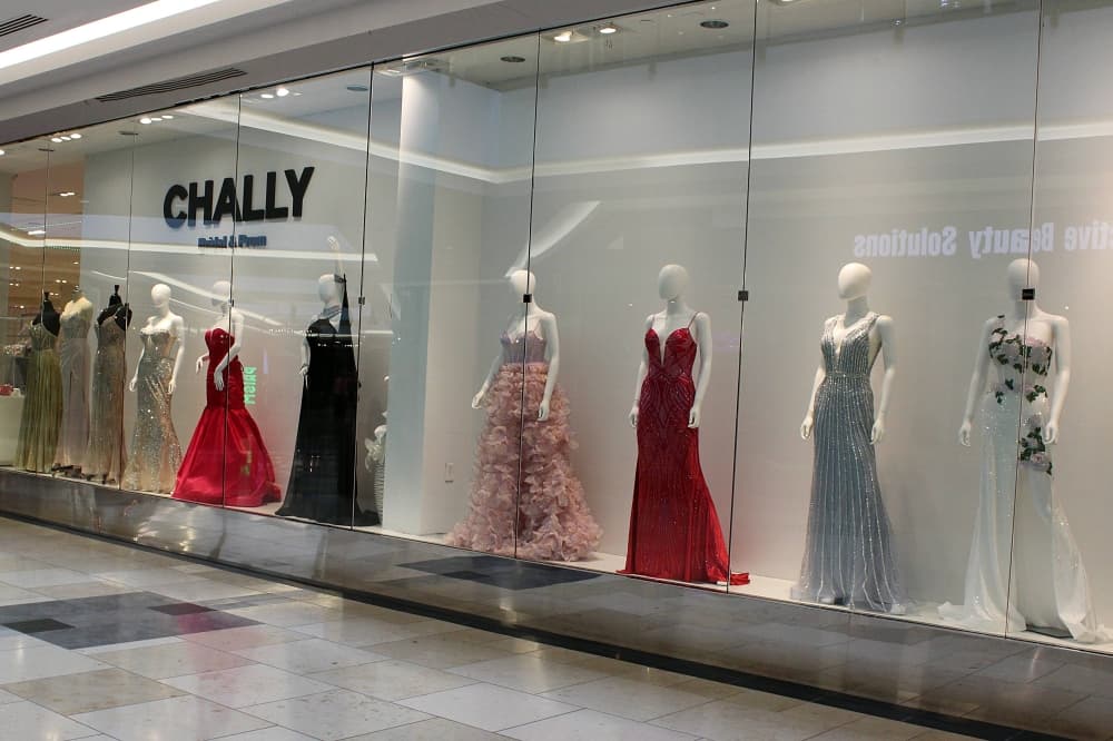 Storefront featuring a variety of special occasion dresses on mannequins. 