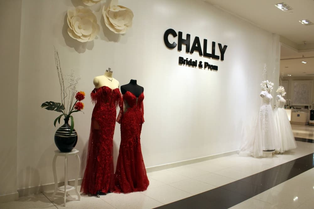Artistically lit wall with Chally Bridal and Prom signage and four mannequins wearing evening and bridal gowns. 
