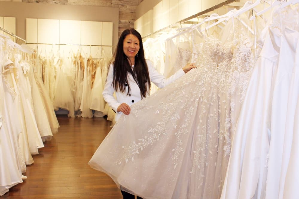 Female in a bridal store holding out the skirt of a bridal gown. 