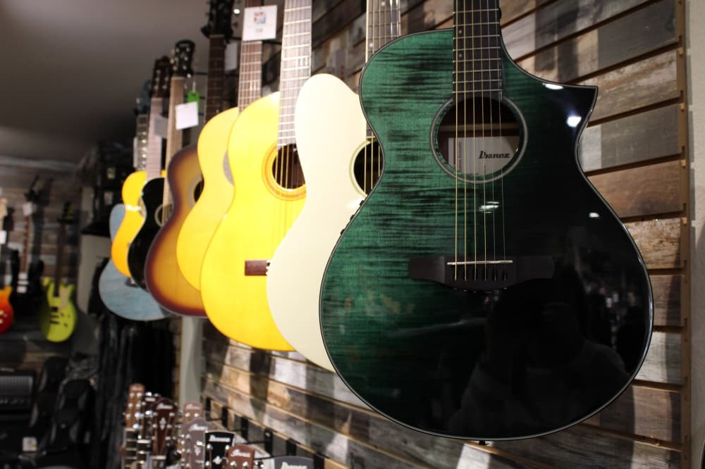 Acoustic guitars hanging side by side on a wall. 