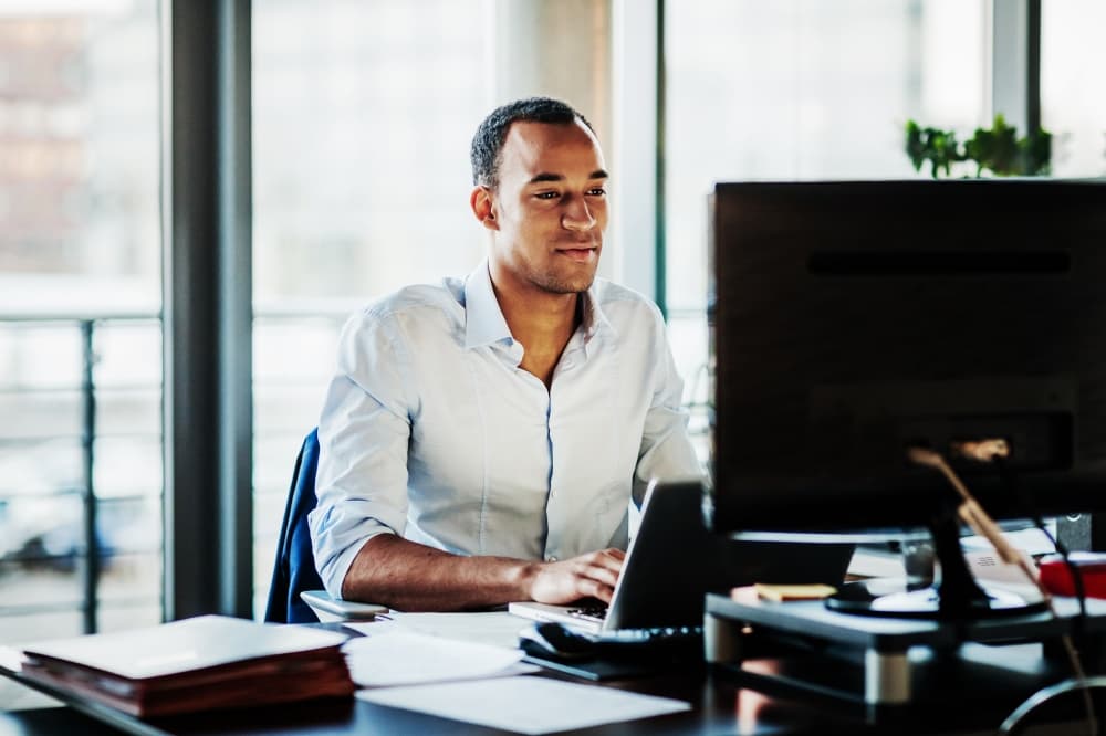 An office worker using working at his desk using a computer to review data.