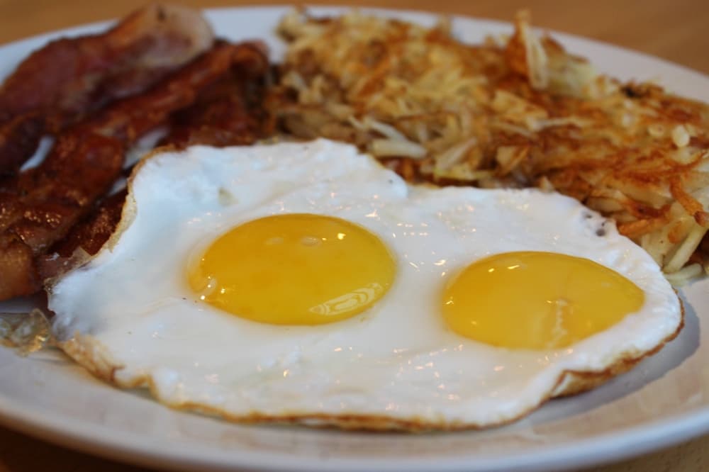 Two sunny-side-up eggs with sides of bacon and hashbrowns. 