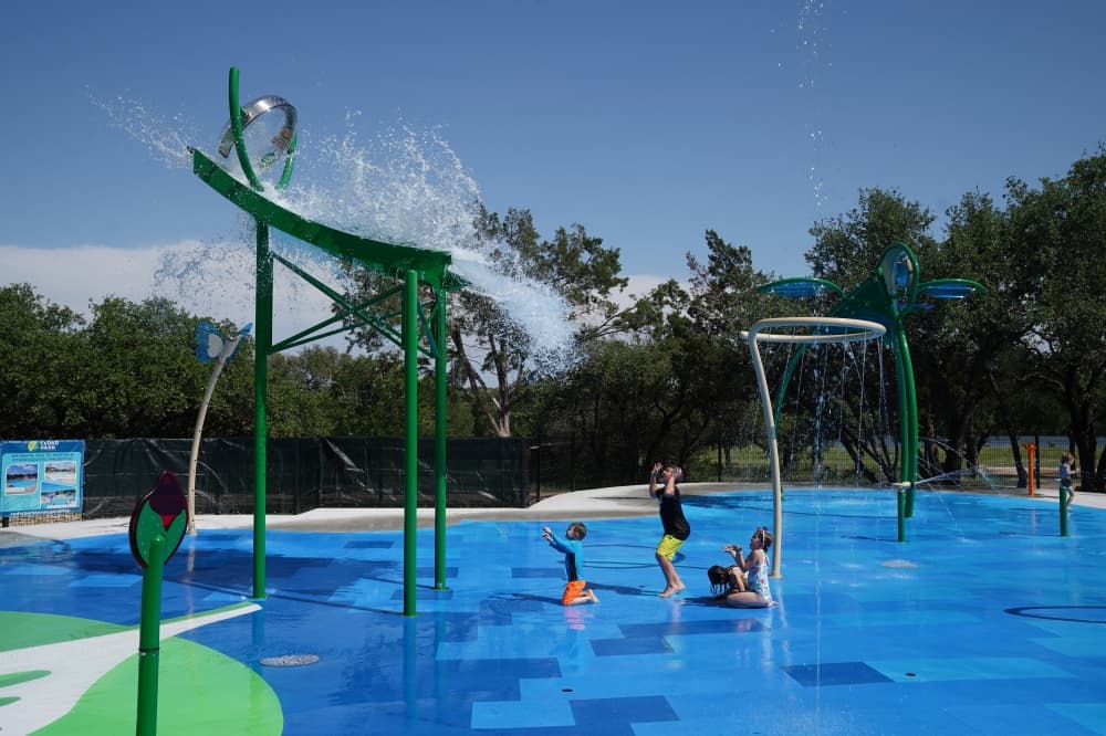 Children wait to have water poured on them from a large tower. 