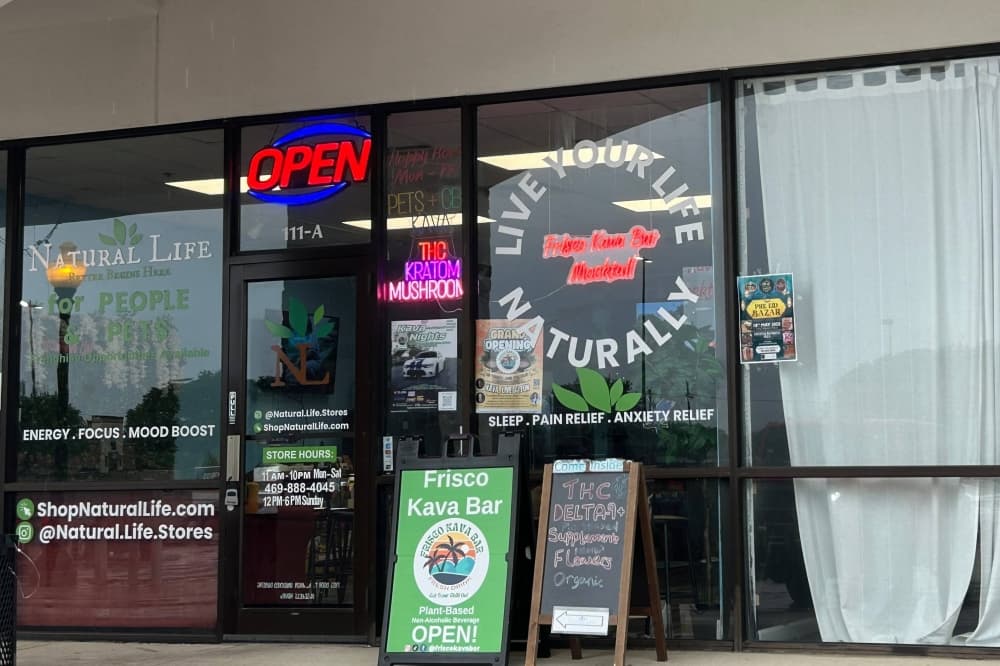 Exterior of a strip mall with a variety of vinyl messages adhered to the store windows. 